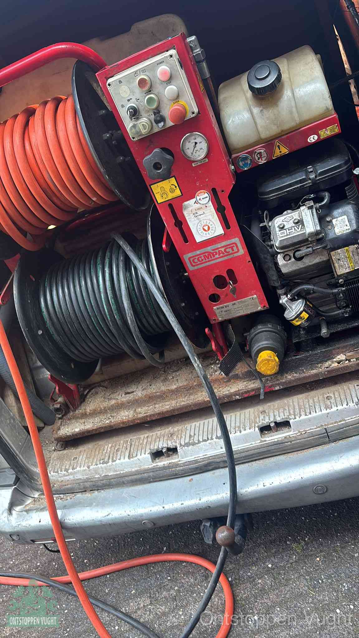 Een rood hogedruk-rioolreinigingstoestel in de laadbak van de bedrijfsbus, apparatuur voor een hardnekkige afvoerverstopping in Vught