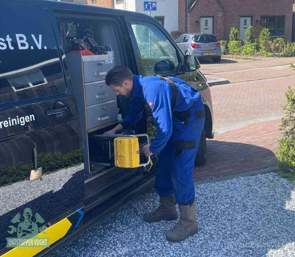Een monteur pakt buiten op de oprit gereedschap uit de bedrijfsbus, het moment om een professional in te schakelen voor een verstopte afvoer in Vught