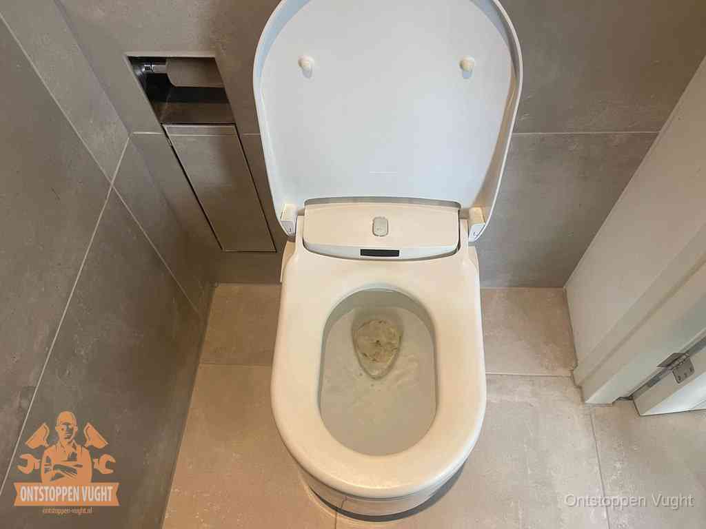 Een wit hangtoilet waarin een prop wc-papier op het water blijft drijven, een duidelijk signaal van een verstopte wc in Vught