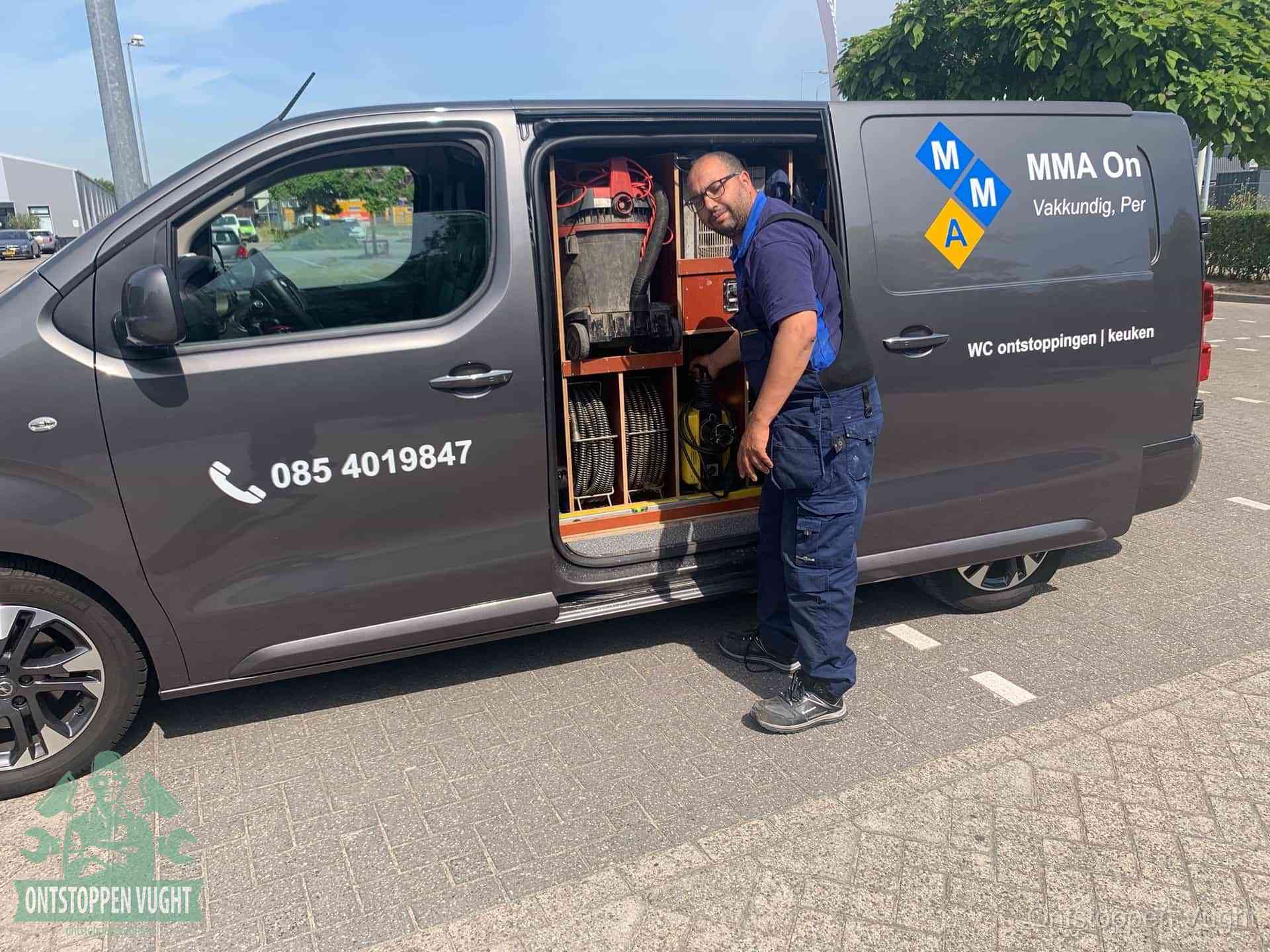 Een monteur bij de open schuifdeur van zijn bedrijfsbus op een parkeerplaats, klaar om de oorzaak van terugkerende afvoerverstoppingen aan te pakken in Vught
