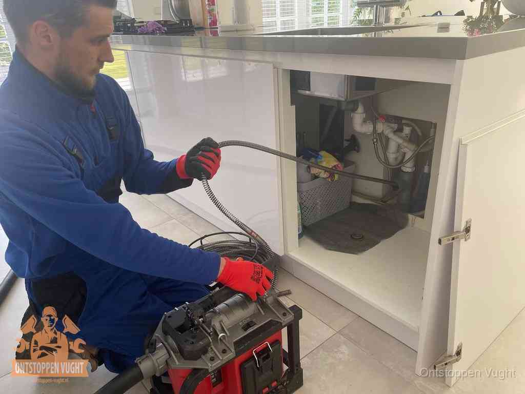 Een monteur reinigt de keukenafvoer grondig met een veermachine om terugkerende gootsteenverstoppingen te voorkomen in Vught