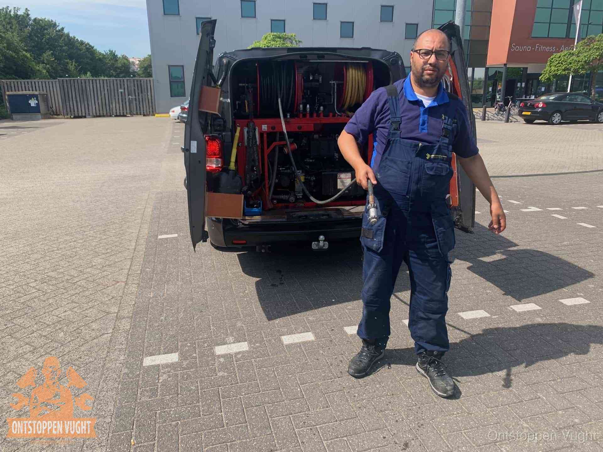 Een monteur bij zijn bestelbus met een hogedruk- en rioolreinigingsunit, klaar om de oorzaak van terugkerende wc-verstoppingen aan te pakken in Vught