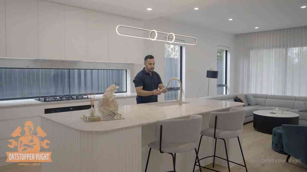 Een bewoner bij de keukenspoelbak die zelf aan de slag gaat met een verstopte gootsteen in Vught